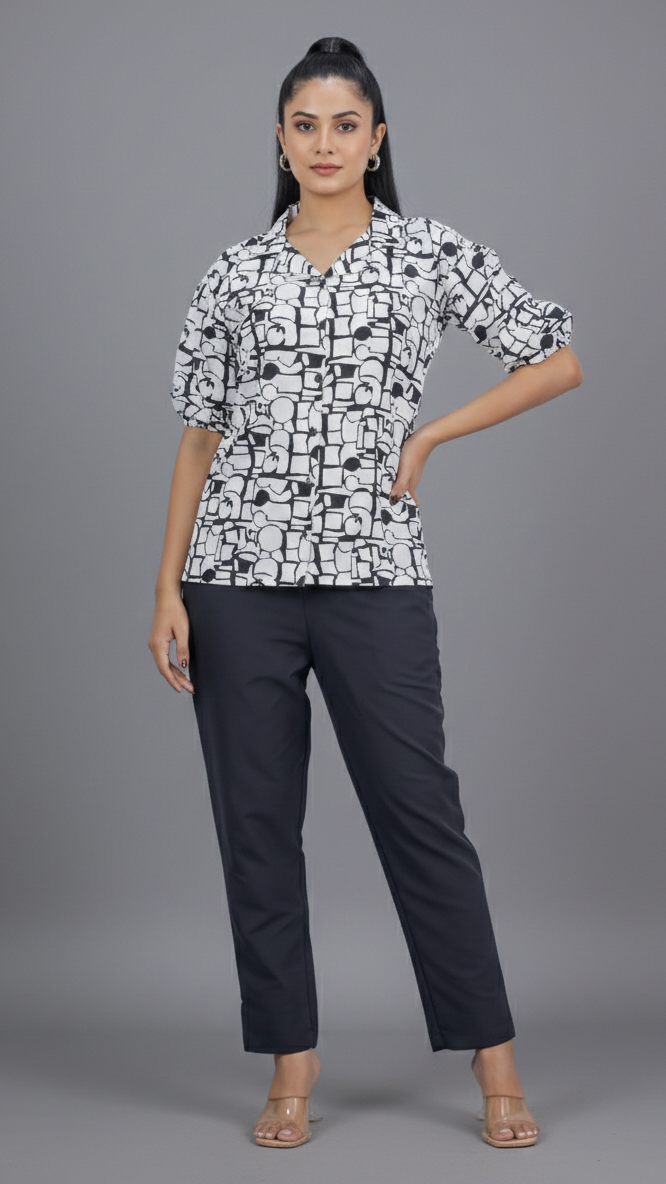 Woman wearing a black and white patterned blouse with black pants on a gray background