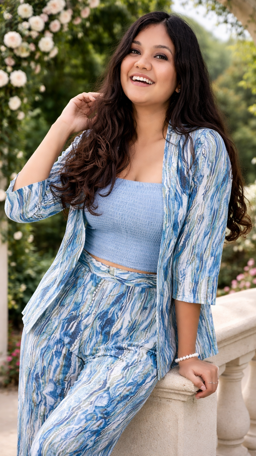 Woman in a blue outfit standing outdoors with greenery in the background