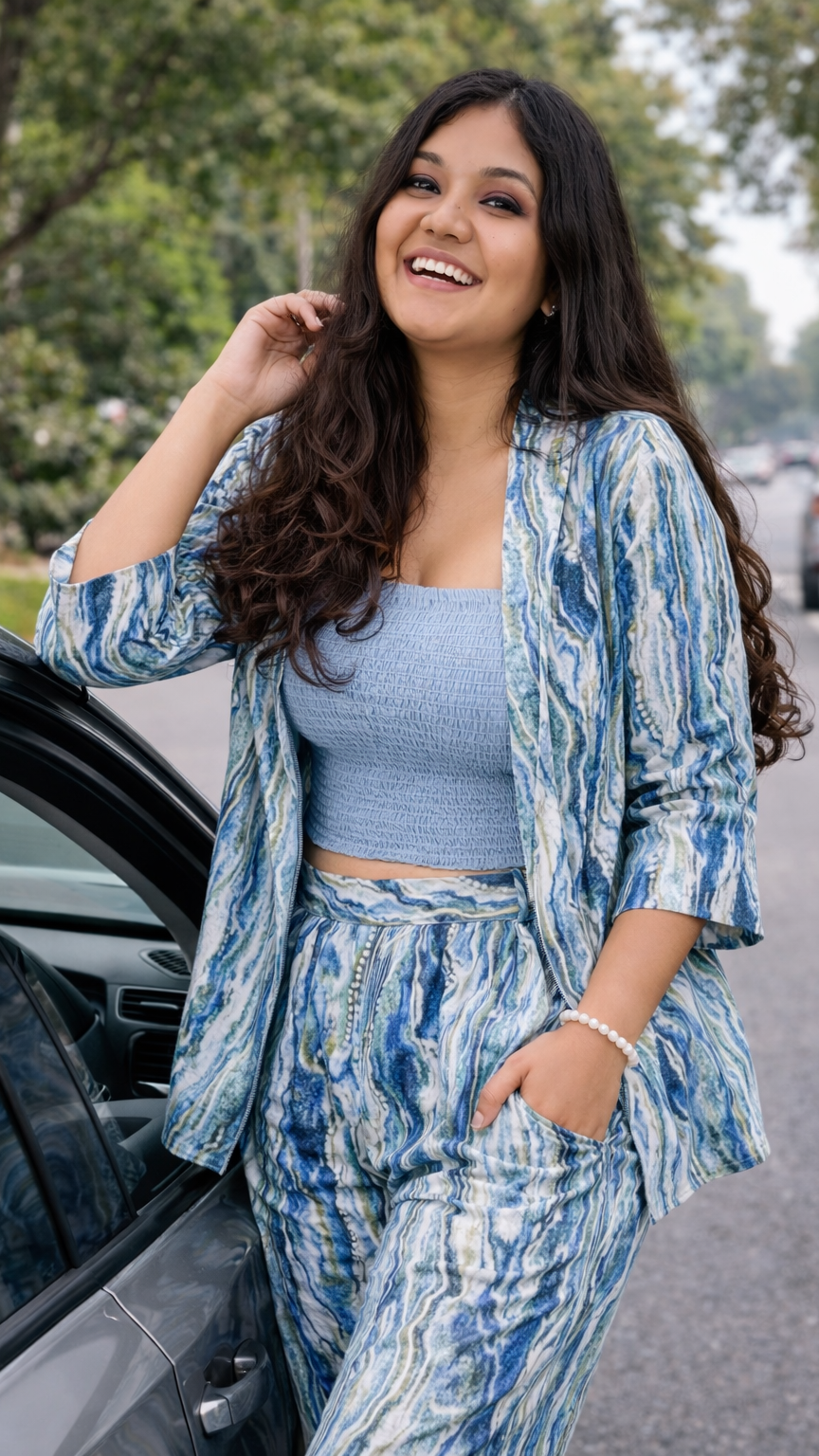 Woman in a blue and white patterned outfit standing next to a car on a street.