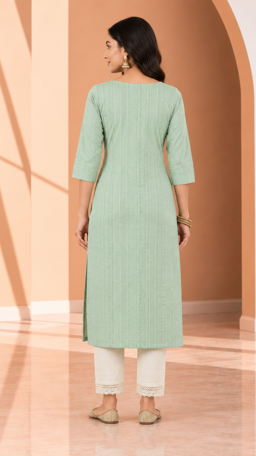 A woman shown from the back wearing a light mint green straight kurta with three-quarter sleeves, paired with off-white pants, standing in a warm-toned studio setting with arches.