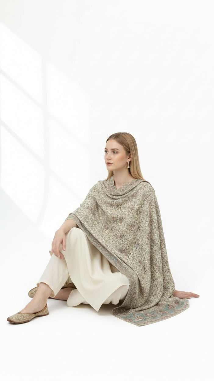 Woman wearing a beige poncho sitting on a white background