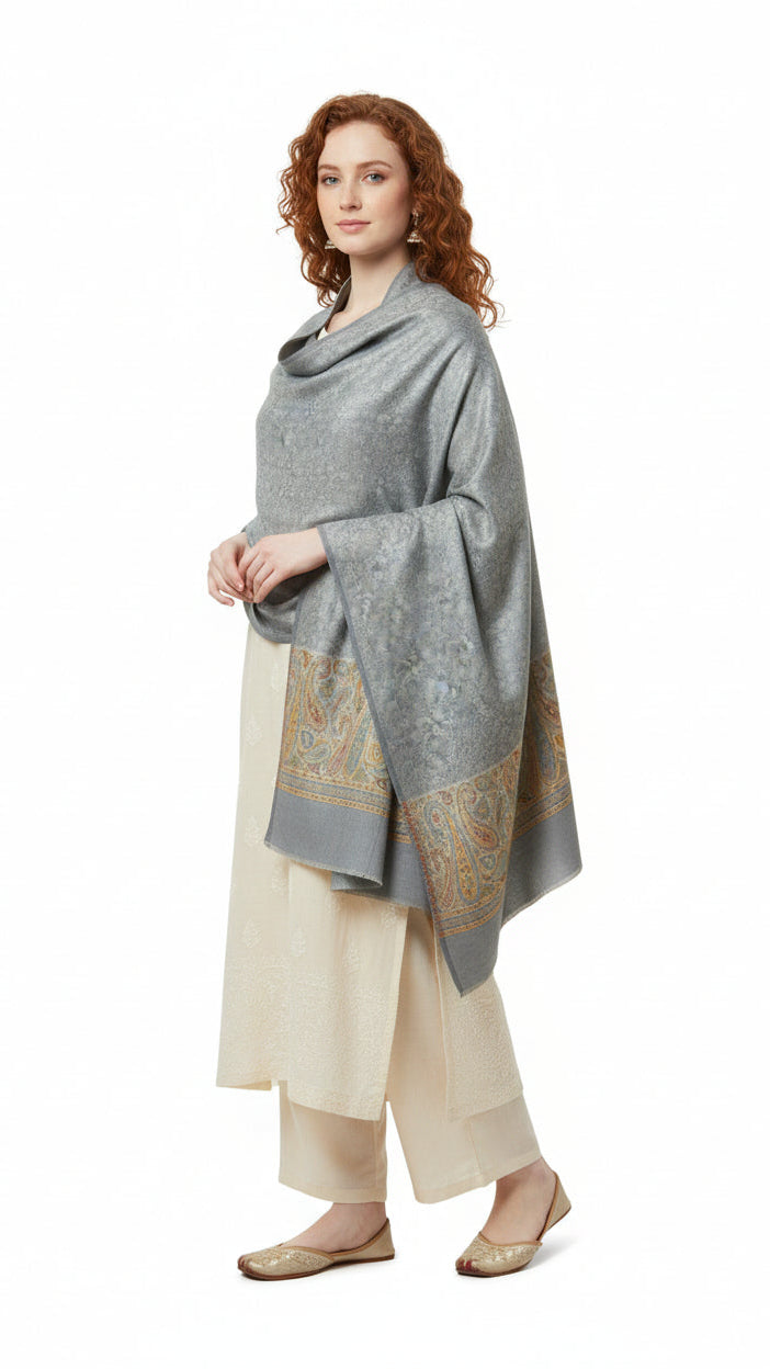 Woman wearing a gray patterned shawl over a cream outfit on a white background