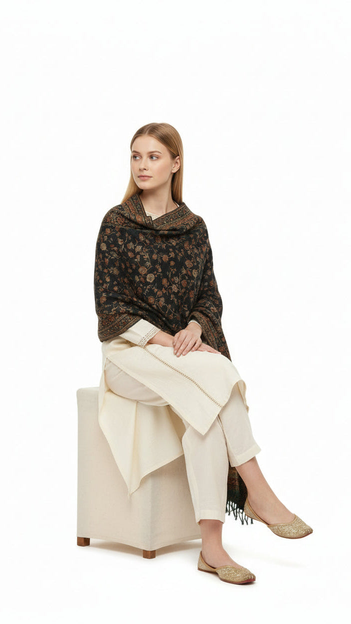 Woman wearing a patterned sweater and beige pants sitting on a white background