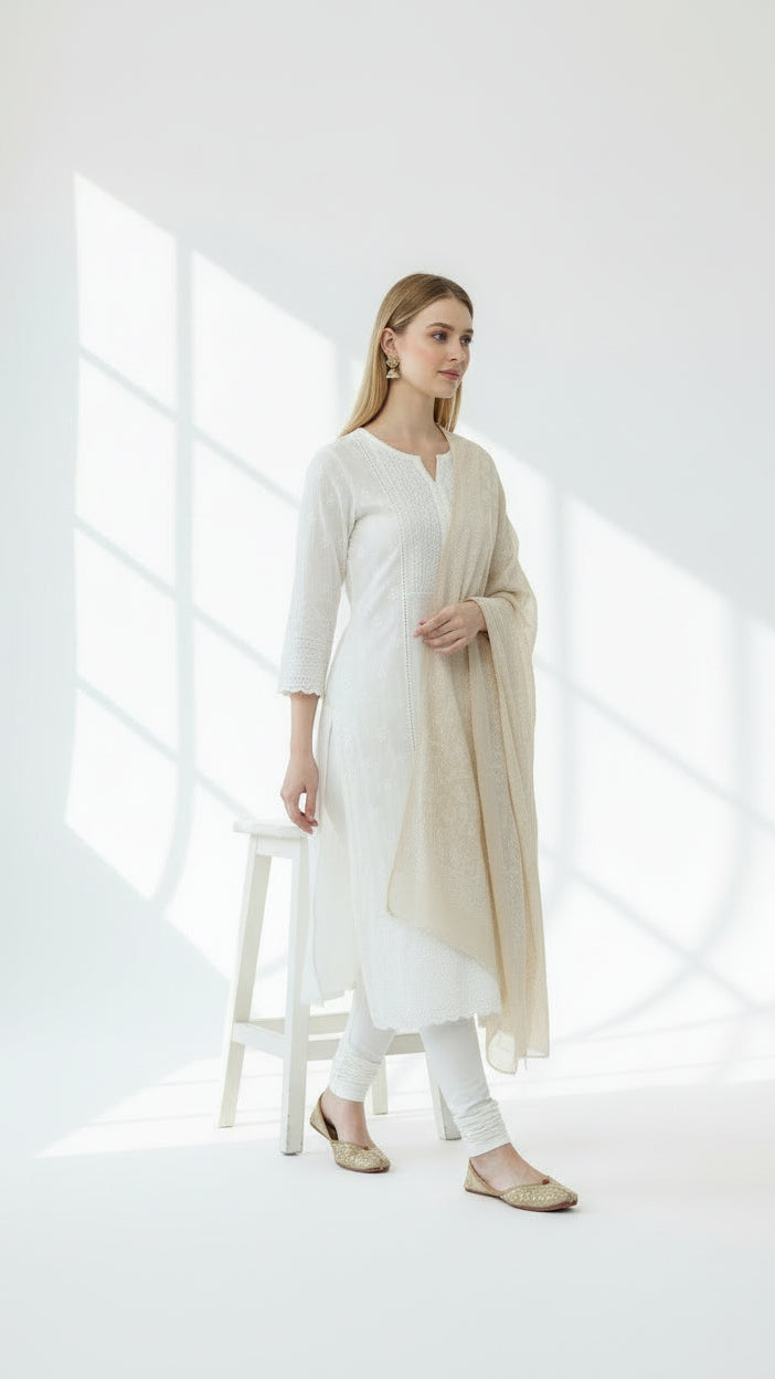 Woman wearing a white outfit with a beige cardigan in a bright, minimalistic setting