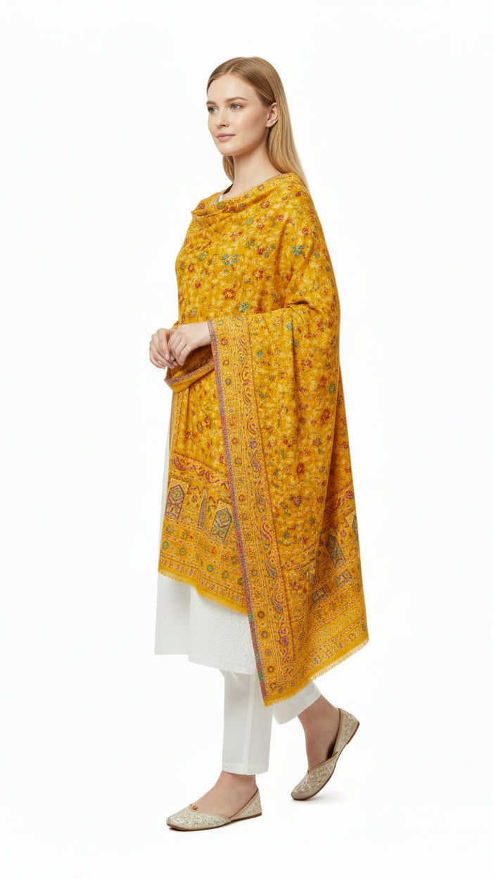 Woman wearing a yellow patterned shawl over a white outfit on a white background