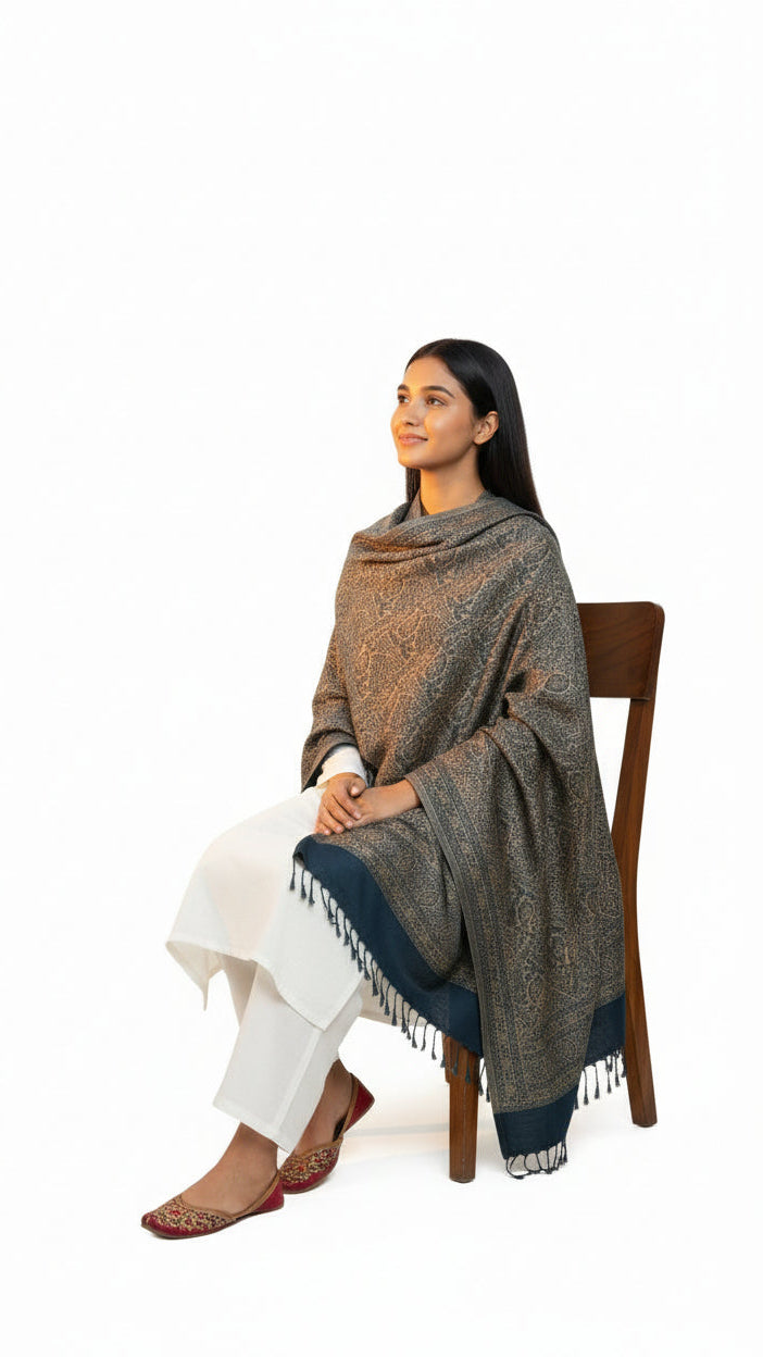 Woman sitting on a chair wearing a patterned shawl on a white background