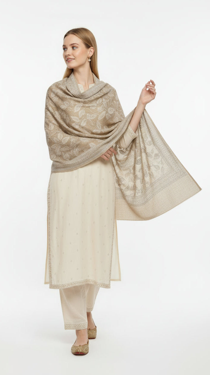 Woman wearing a beige patterned shawl over a cream outfit on a white background