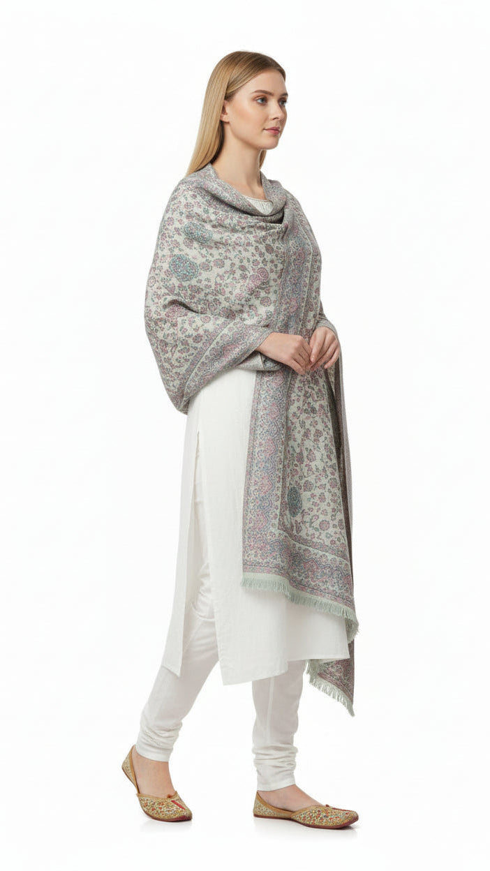 Woman wearing a patterned shawl over a white outfit on a white background