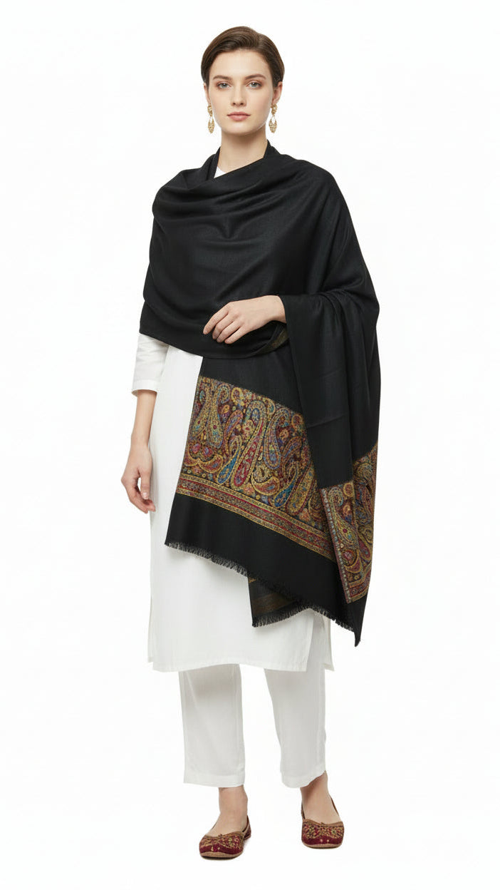 Woman wearing a black shawl with intricate patterns over a white outfit on a white background