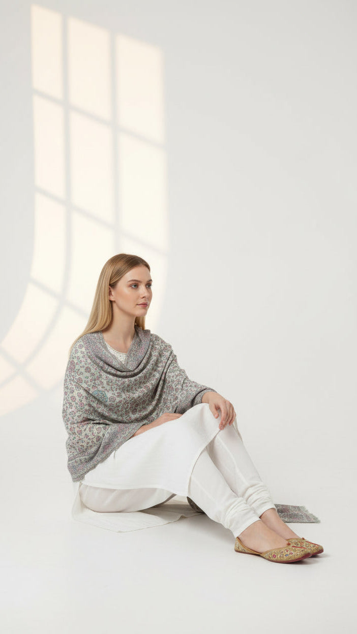 Woman sitting on a white floor in a minimalistic room with large windows.