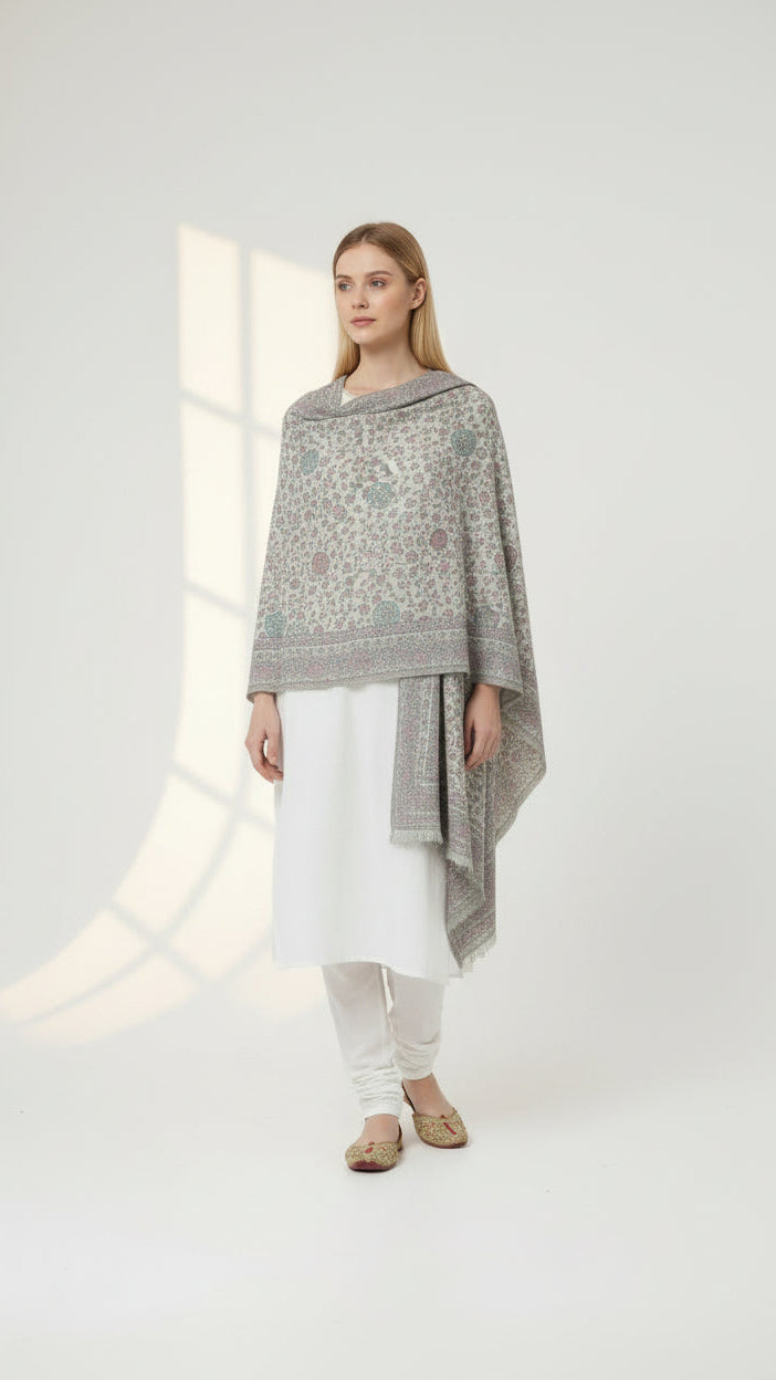 Woman wearing a gray patterned poncho over a white outfit on a light background