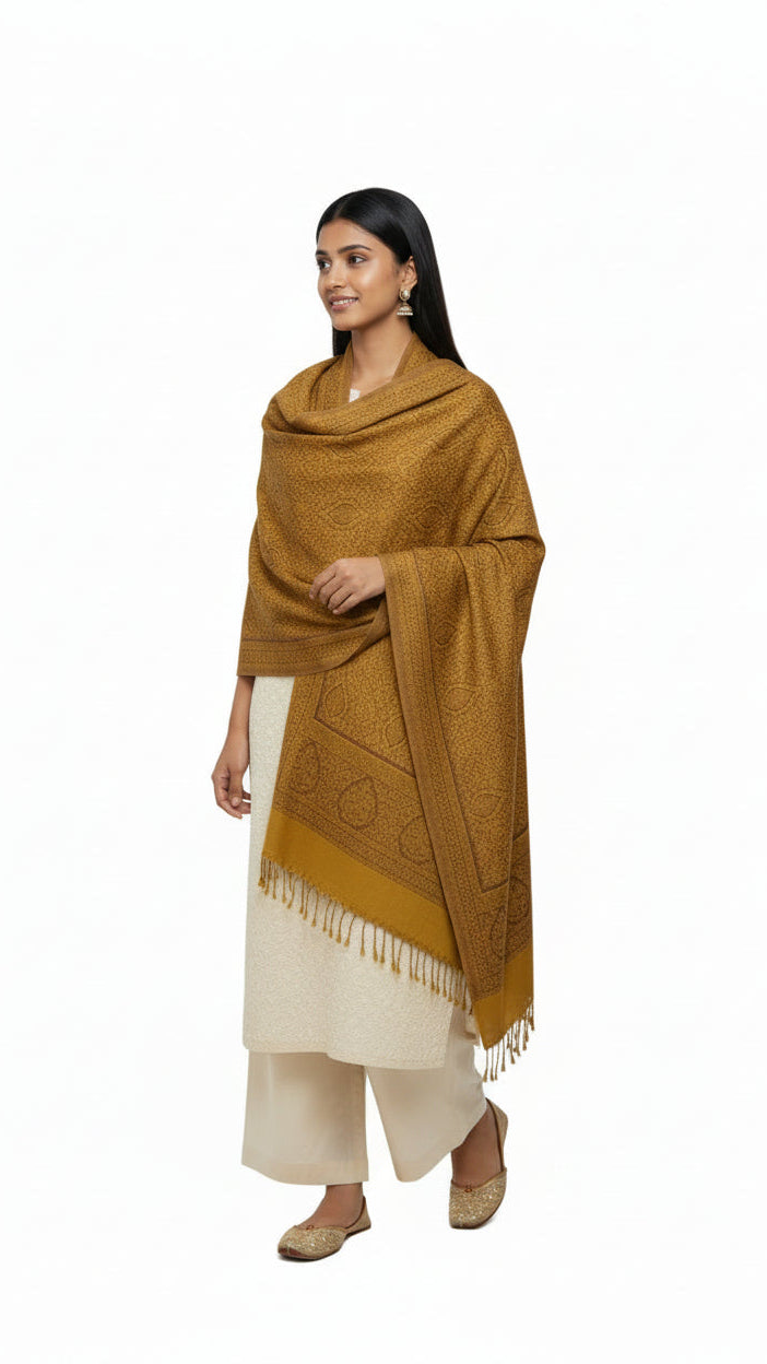 Woman wearing a mustard yellow shawl over a cream outfit on a white background