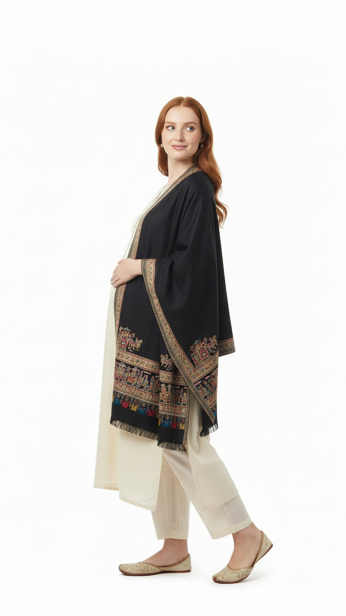 Woman wearing a black and gold embroidered shawl over a white outfit on a white background