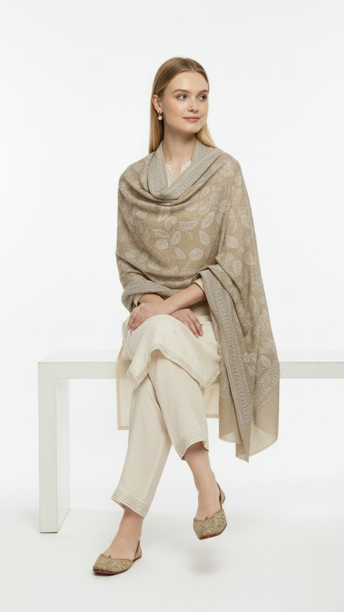 Woman wearing a beige patterned shawl over a cream outfit on a white background