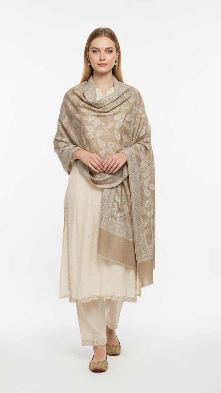 Woman wearing a beige patterned shawl over a cream outfit on a white background